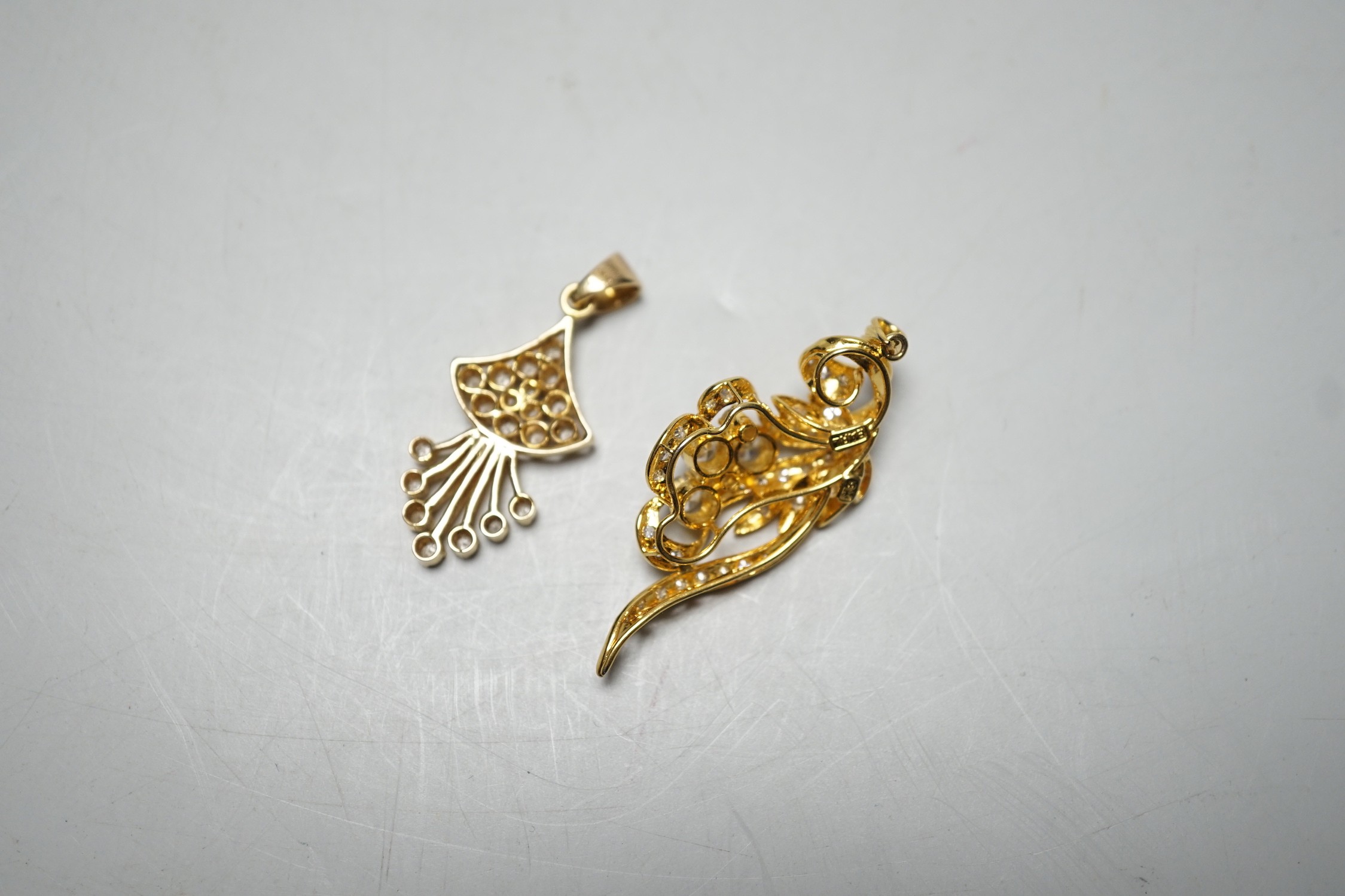 An Earl 18k yellow metal and diamond cluster ser scrolling pendant, overall 46mm and a yellow metal and diamond cluster set fan shaped pendant, gross weight 11.8 grams.